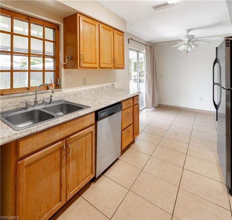 The kitchen features wood cabinetry, a double basin stainless steel sink, and light-colored countertops