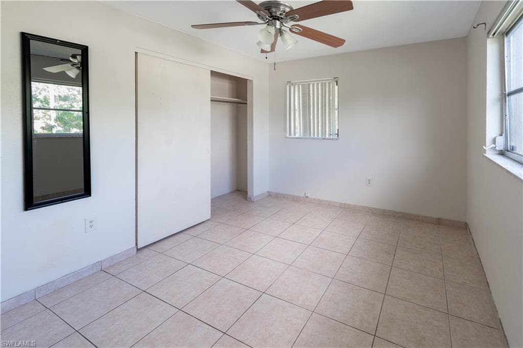 This room features tiled flooring, a ceiling fan with light fixture, and windows providing natural light