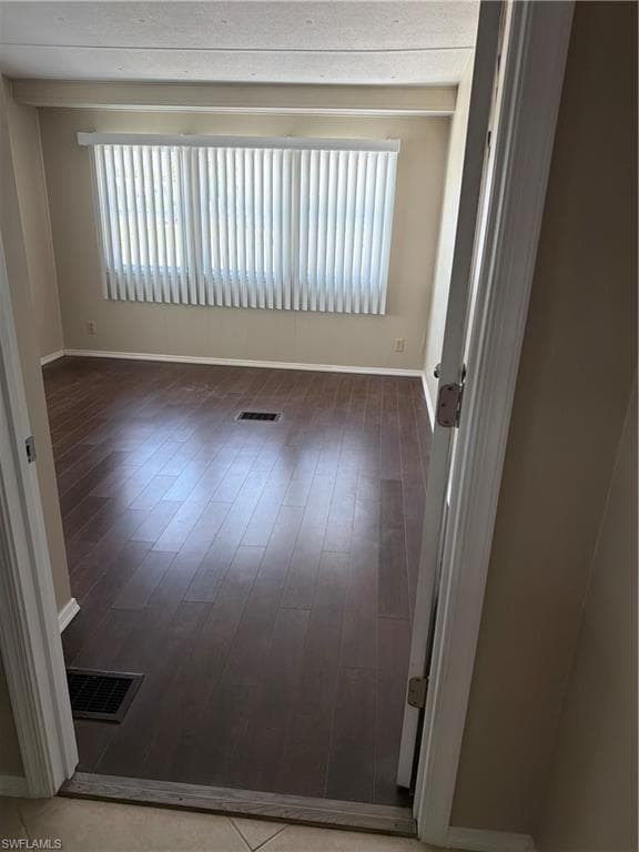 Could be used as a bedroom, office or bonus room. Interior room featuring dark wood-finish flooring, light tan wall color, and a large window with vertical blinds