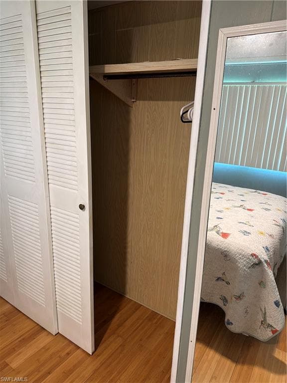 Louvered bi-fold closet doors revealing wood-finish interior paneling, a single shelf, and a clothing rod