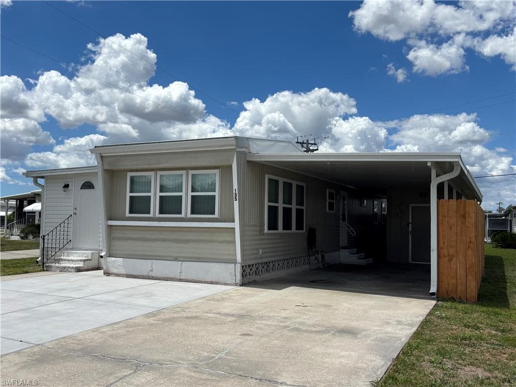 The property features a light-colored exterior, a white front door with a decorative window, and multiple windows with white frames