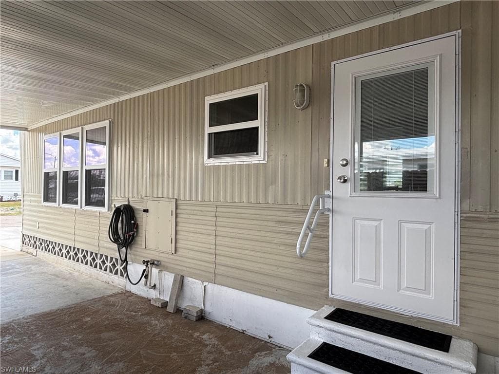 The property features a covered entryway with a white door that includes a glass panel