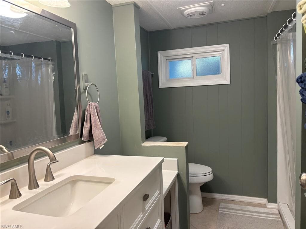 Bathroom with a white vanity featuring a rectangular sink and brushed nickel faucet, a large mirror, and a window providing natural light