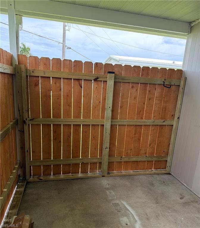 Fenced outdoor area featuring a concrete slab, wood privacy fence, and a gate with black hardware