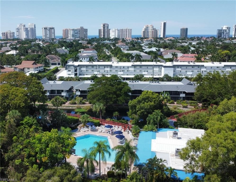 The property features a swimming pool with adjacent lounge chairs and umbrellas, surrounded by mature trees and lush landscaping
