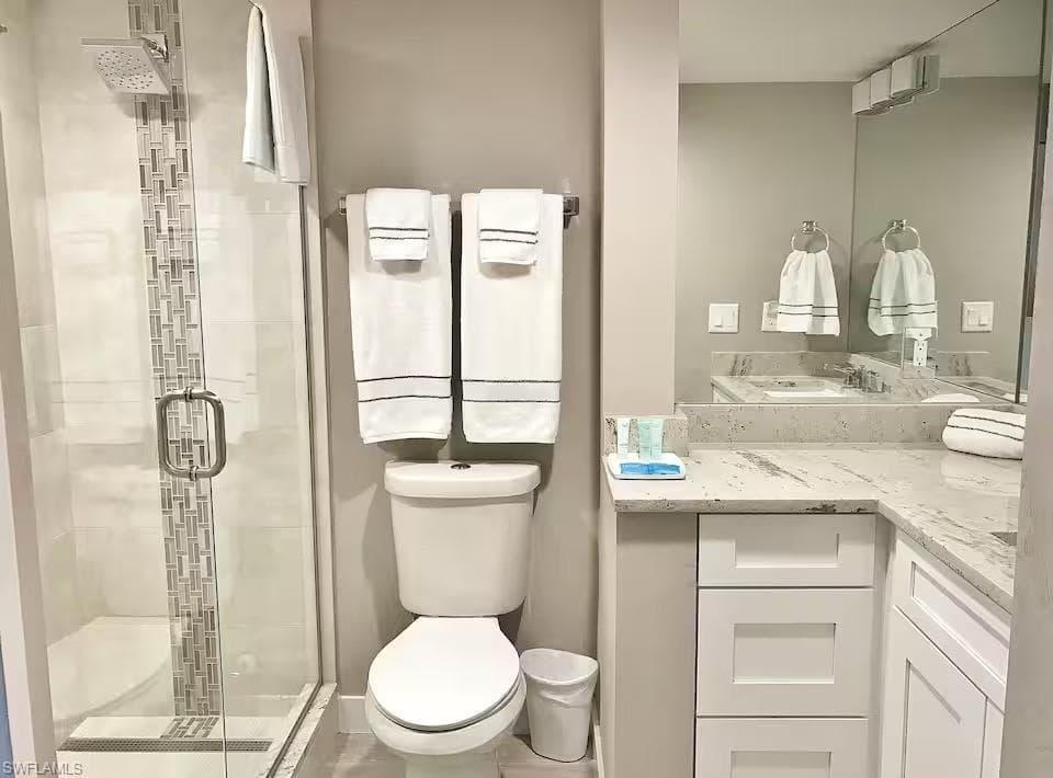 This bathroom features a contemporary shower with a glass enclosure and decorative tile inlay, alongside a white toilet
