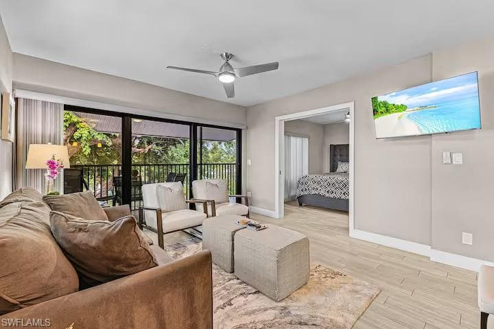 Living area featuring a ceiling fan, light-toned flooring, and a sliding glass door opening to a balcony