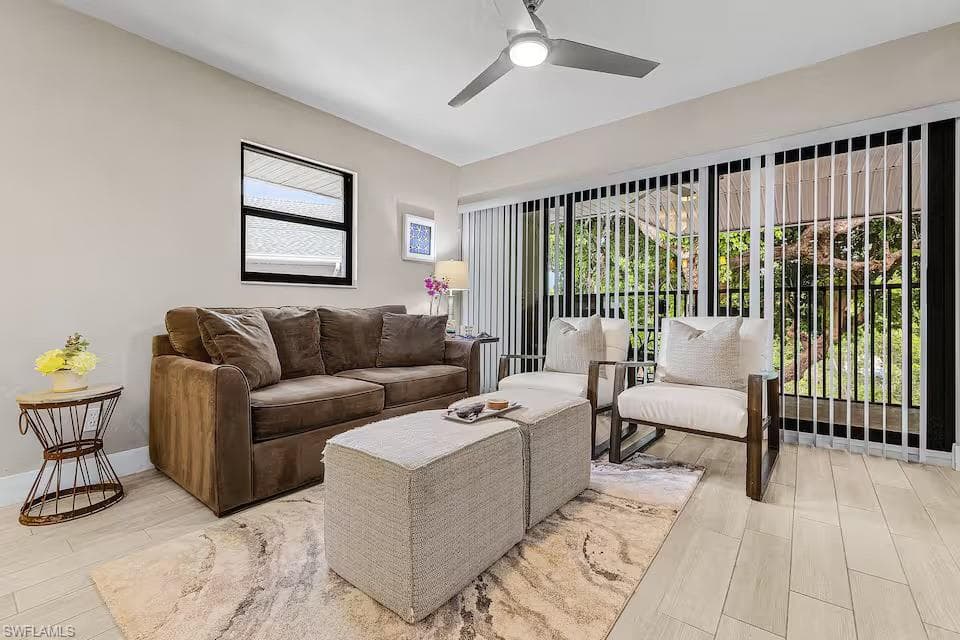 The living area features light-colored flooring, a large window, and sliding glass doors with vertical blinds