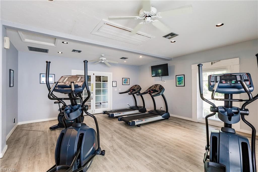This fitness area features light gray walls, recessed lighting, and ceiling fans