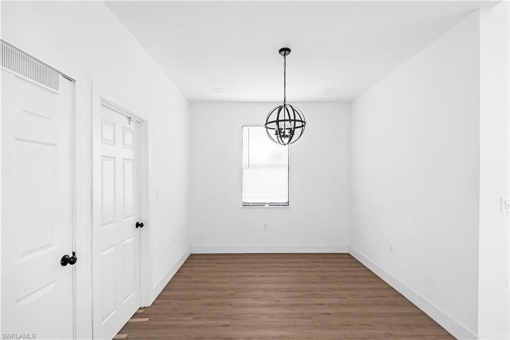 Open concept room featuring a contemporary orb chandelier, white trim, and wood-finish flooring