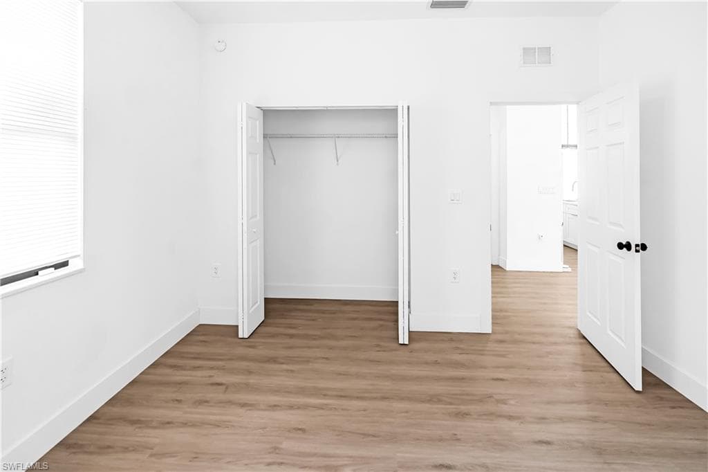 Room featuring wood-finish flooring, crisp white walls, and bright white baseboards