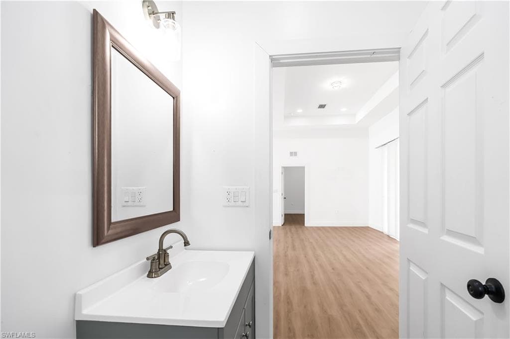 Bathroom vanity with a white rectangular sink, a two-handle faucet, and a framed mirror