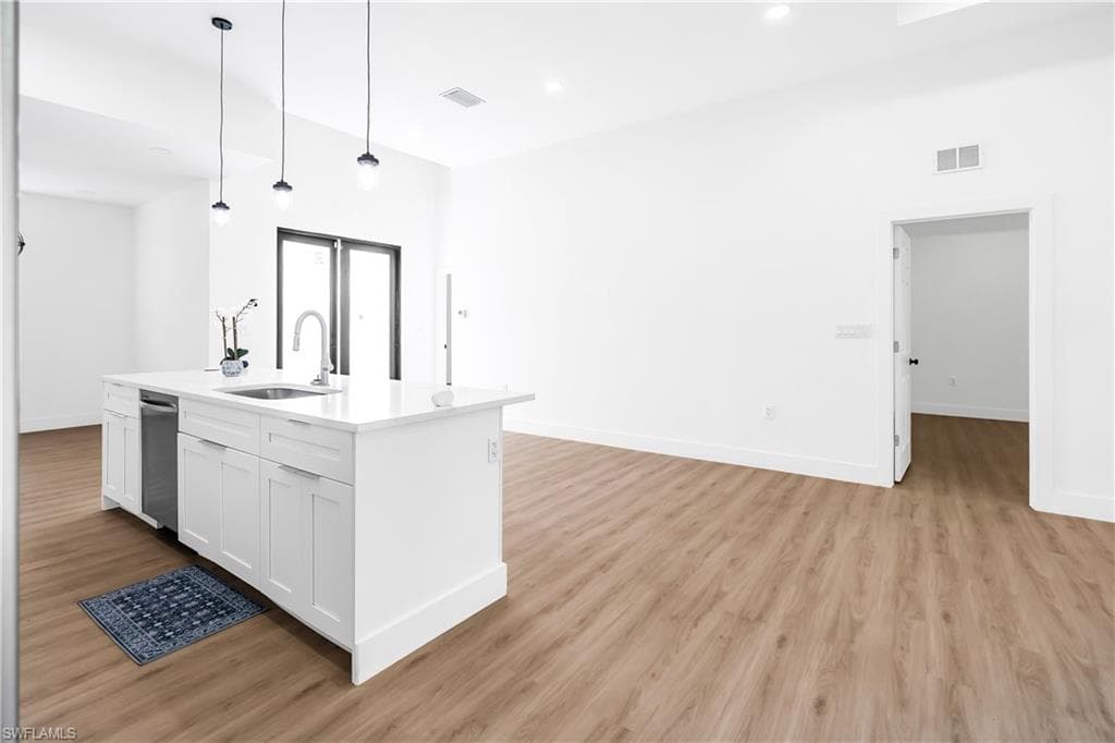 Kitchen island with white shaker cabinetry, an undermount sink, and a stainless steel dishwasher