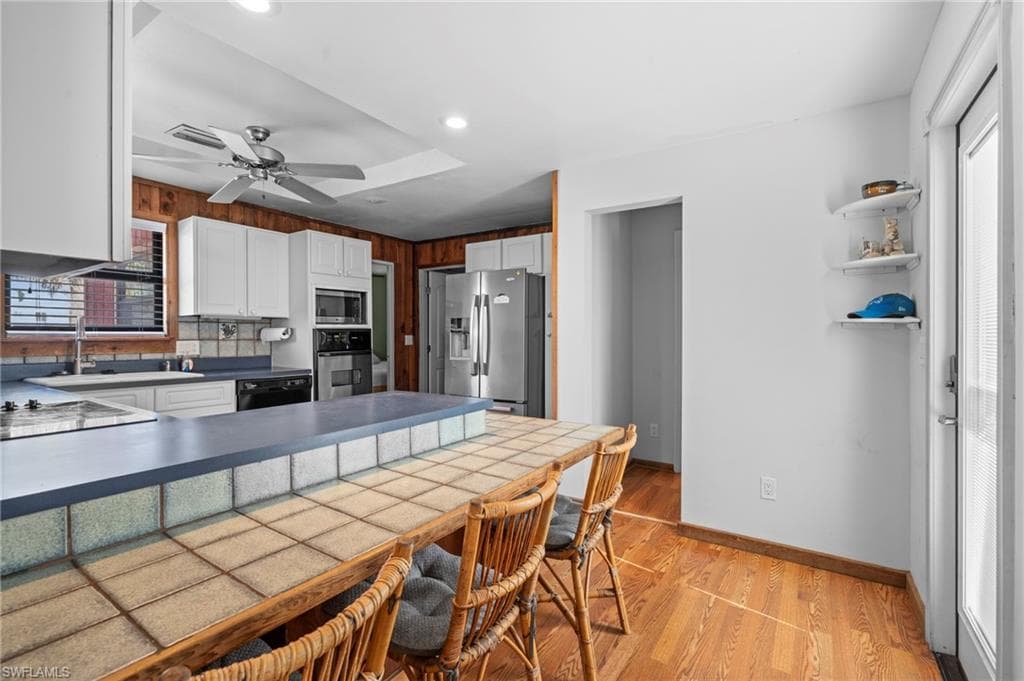 Kitchen with tiled breakfast bar, wood accents, and modern stainless steel appliances - Virtually Edited Image