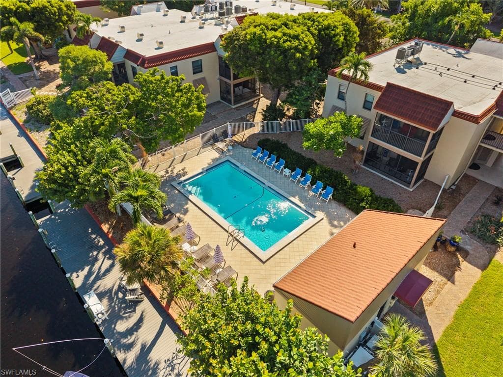 Outdoor swimming pool with a paved surround, multiple lounge chairs, and a long dock
