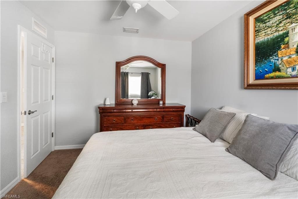 Bedroom featuring light gray walls, brown carpet flooring, and a white ceiling fan