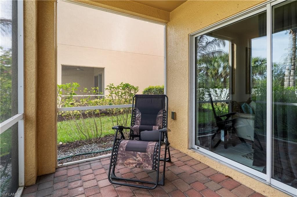 Screened patio featuring brick paver flooring and textured stucco walls