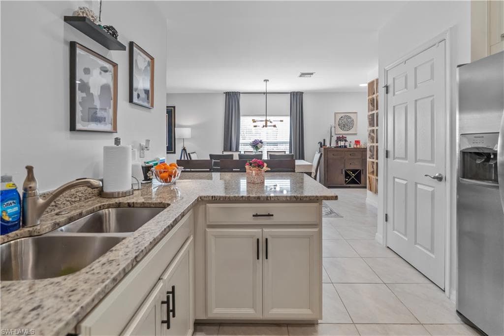 Kitchen featuring light-toned cabinetry, a double basin stainless steel sink, and a speckled countertop