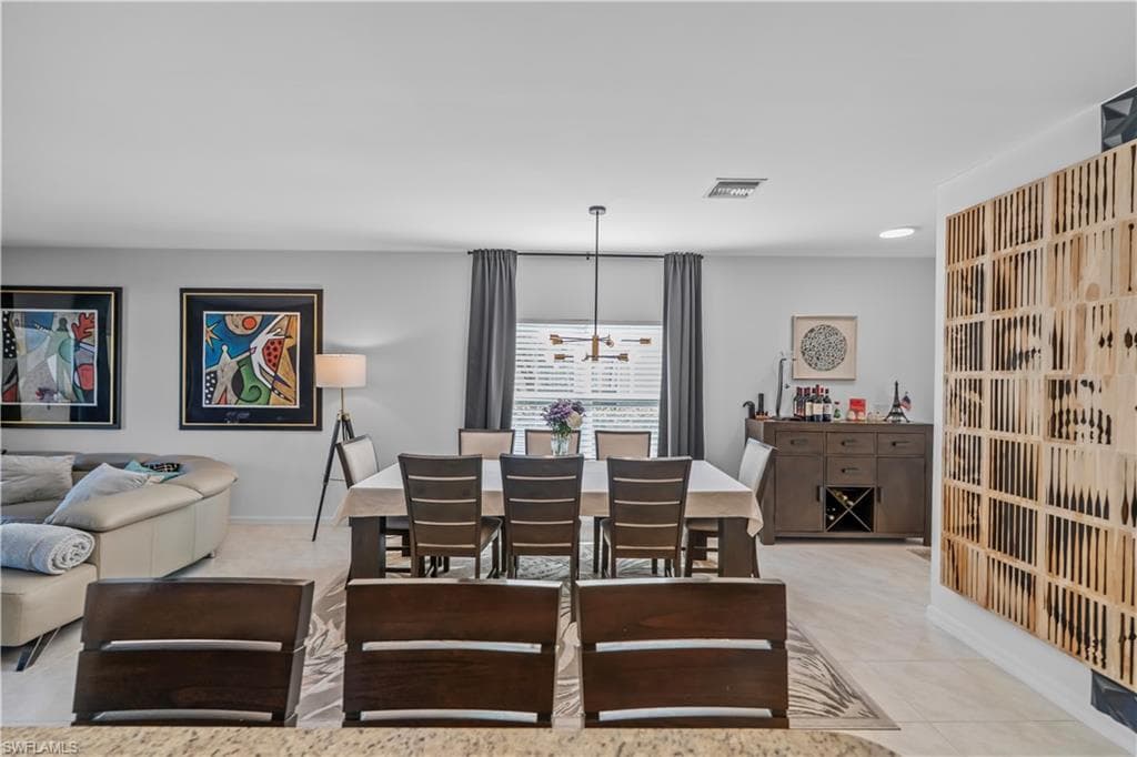 Open-concept living and dining area featuring tile flooring, contemporary lighting fixture, and a built-in buffet with wine storage