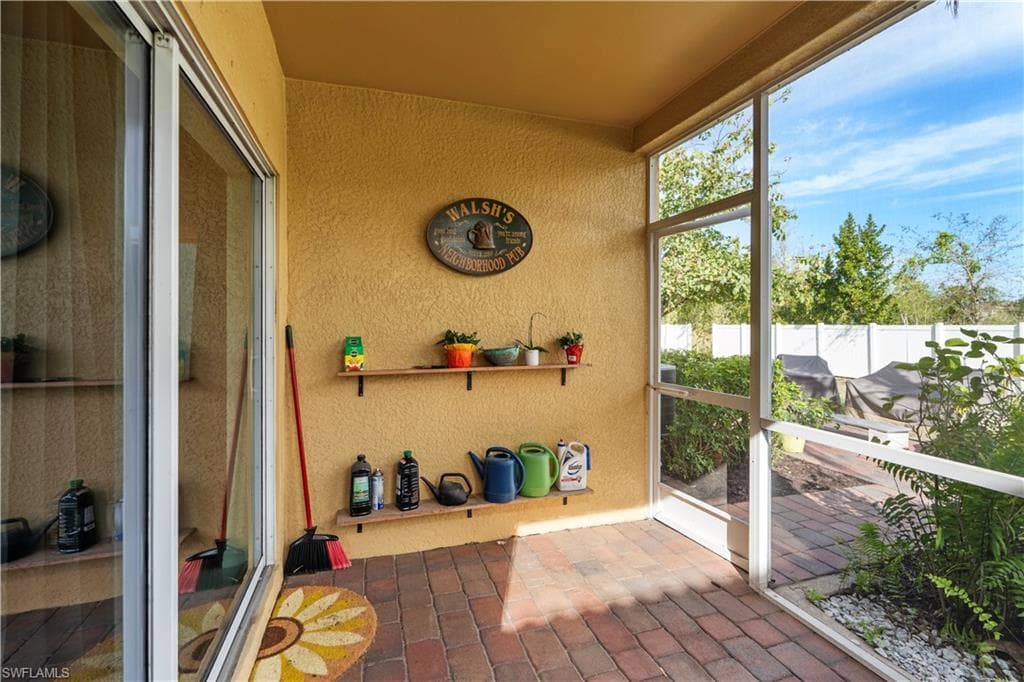 Screened patio featuring brick paver flooring, built-in shelving, and a sliding glass door