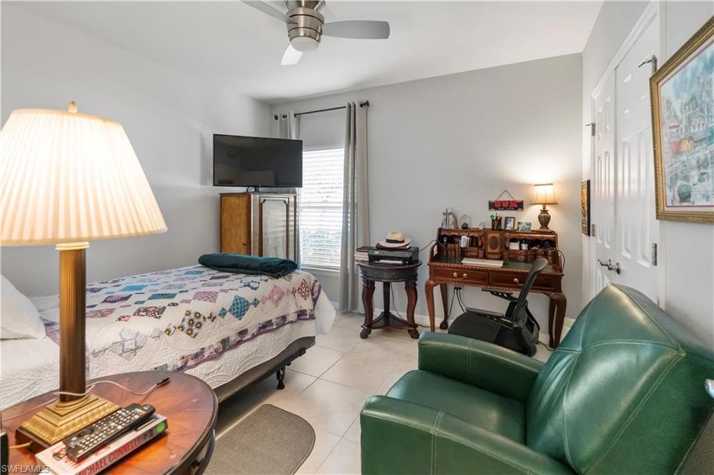 Room featuring light neutral wall paint, tile flooring, a window with horizontal blinds and drapery, a ceiling fan, and a paneled white door