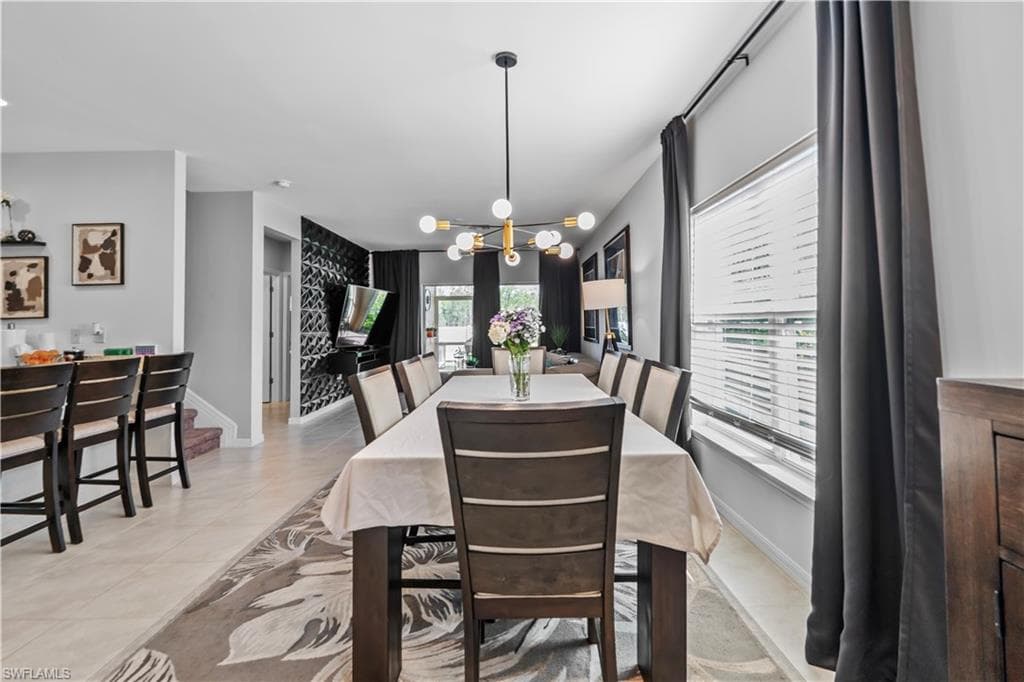Dining area featuring a dark wood-finish table with upholstered chairs, an overhead modern chandelier with globe lights, and a window with blinds and dark drapery