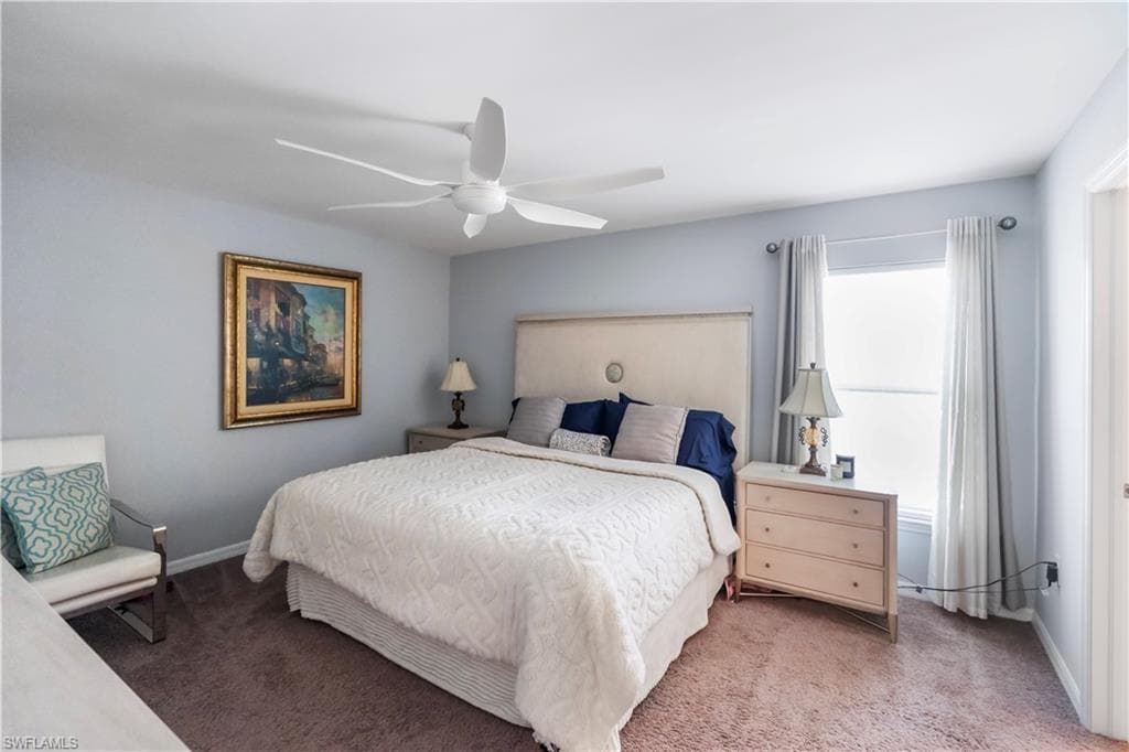 Carpeted bedroom with a multi-blade ceiling fan, a window with drapes, and a built-in closet door