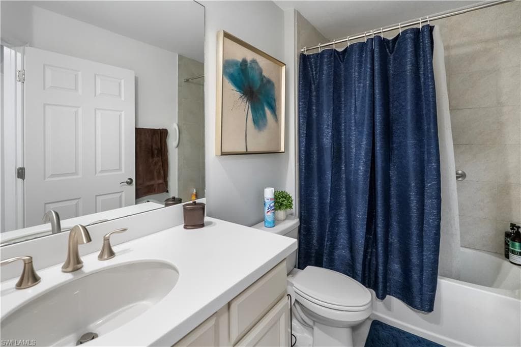 Bathroom featuring a white vanity with an integrated sink, brushed nickel faucet, full-width wall mirror, and a white toilet