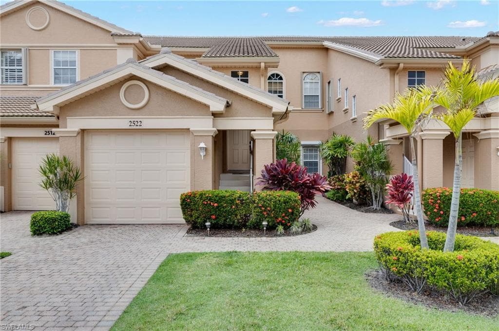 Stucco exterior featuring a tiled roof and paver driveway
