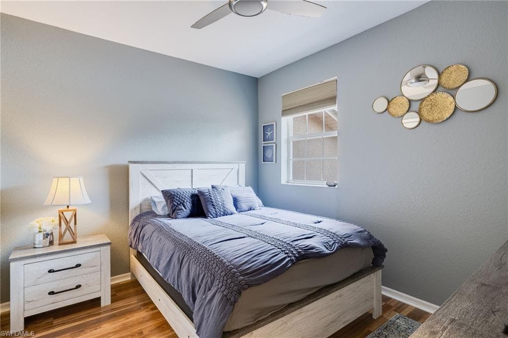 Bedroom featuring wood-finish flooring, a double-paned window, and a ceiling fan