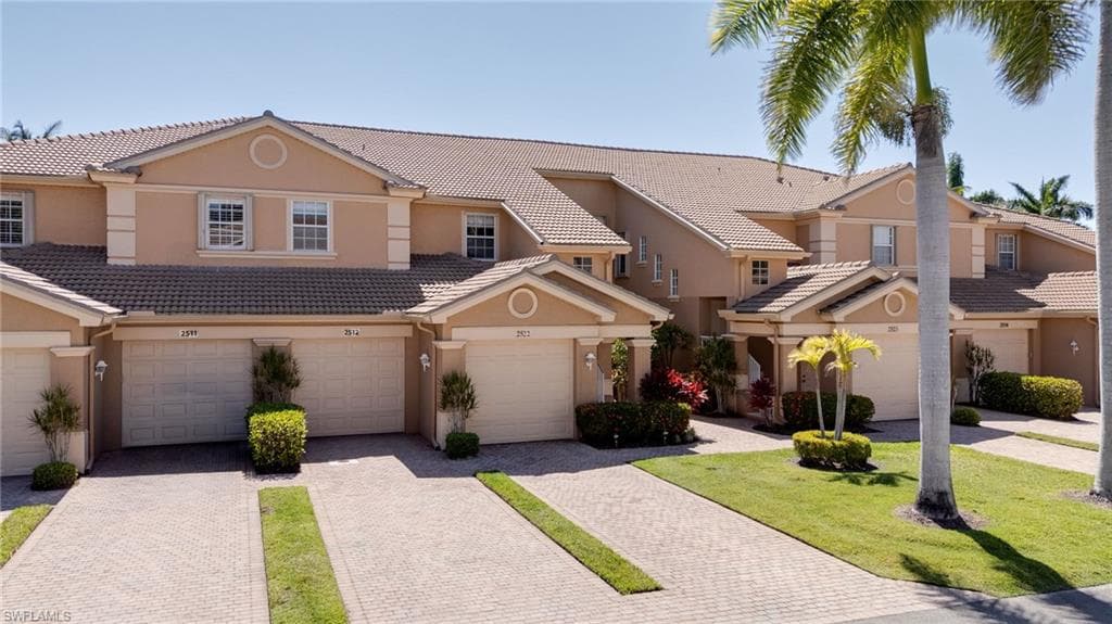 Multi-unit residential property featuring a stucco exterior, tile roofs, and individual garage doors