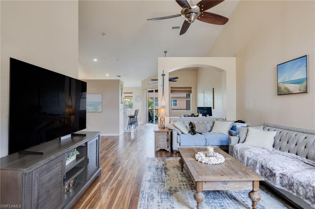 Spacious living area featuring vaulted ceilings, wood-finish flooring, and recessed lighting