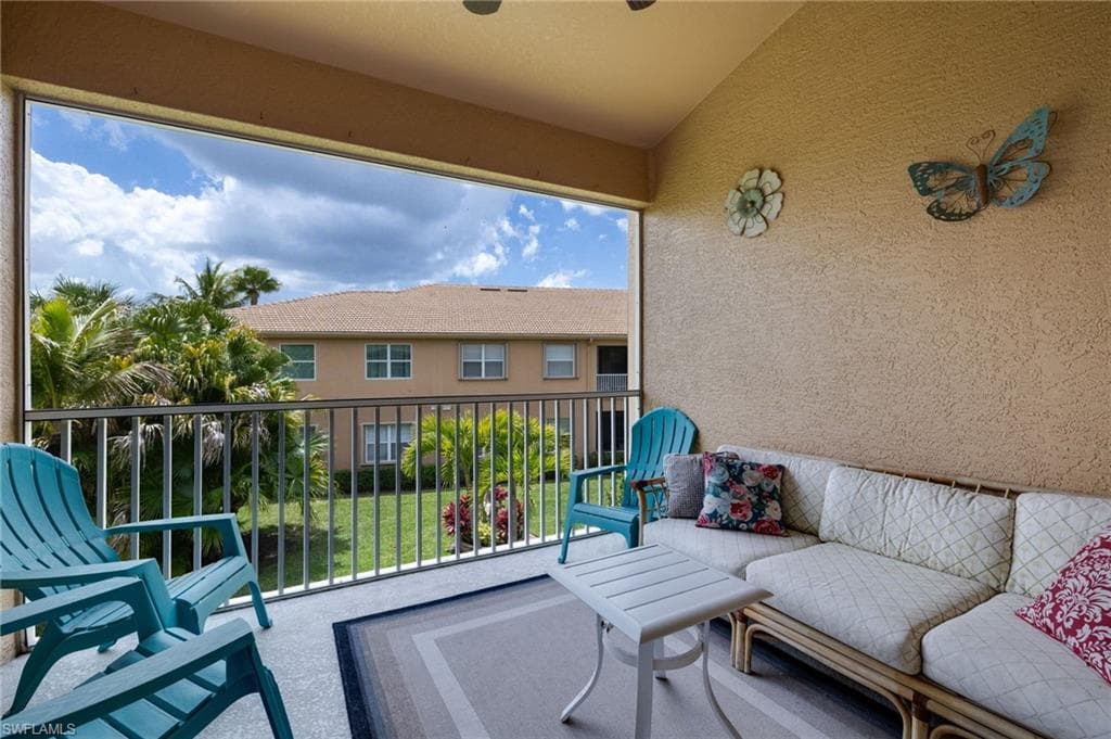 Screened balcony featuring a textured wall, tile flooring, and a metal railing