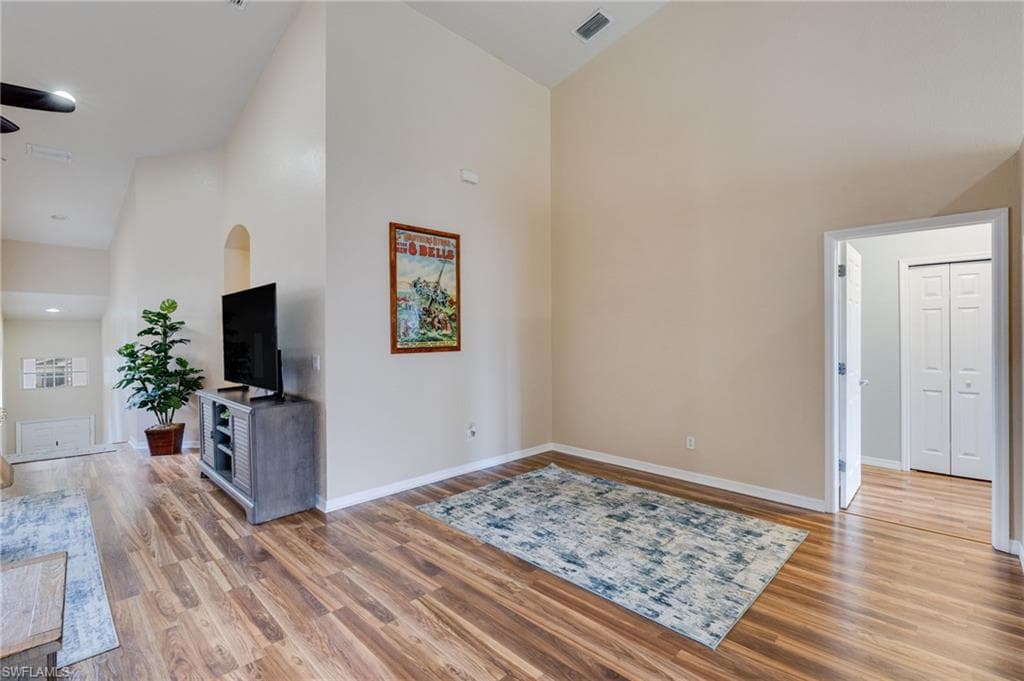 High ceilings featuring sloped architectural elements, wood-finish flooring, and light neutral wall tones