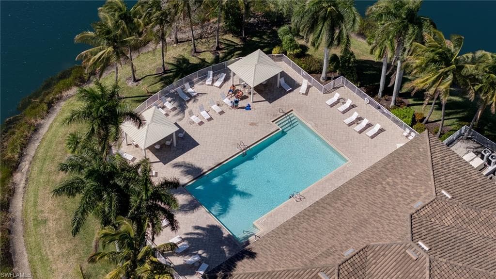 Outdoor swimming pool with a surrounding paved deck, enclosed by a white privacy fence