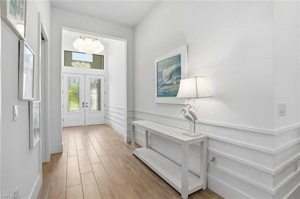 Grand entryway featuring double doors with decorative glass panels and a transom window