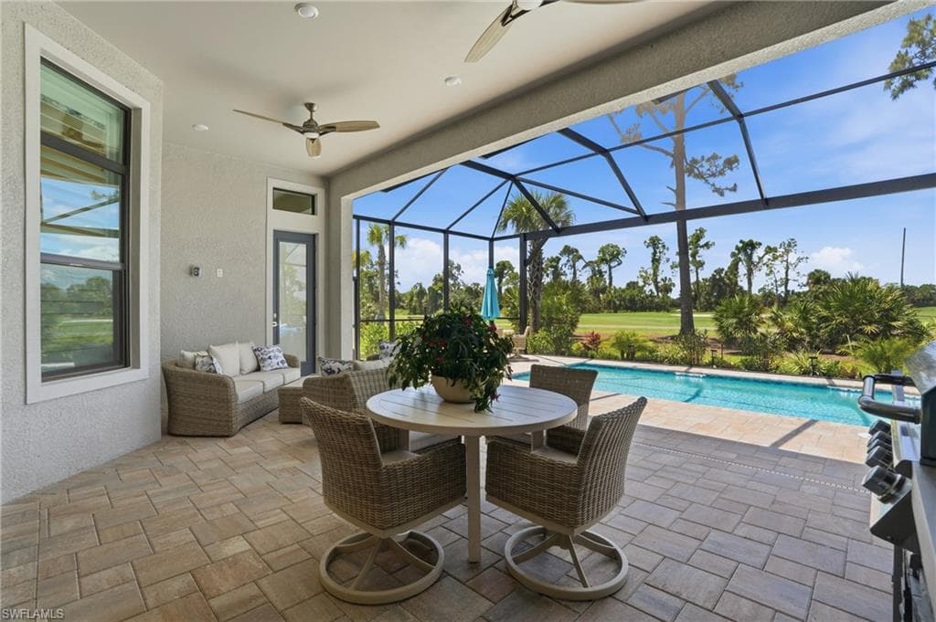 Screened lanai featuring a paver patio, a built-in outdoor grill, a rectangular swimming pool, and tropical landscaping