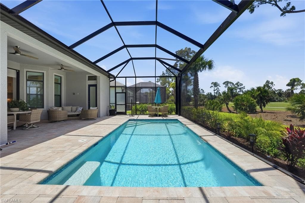 Screened lanai featuring an in-ground swimming pool with integrated steps, paver decking, and a covered patio area
