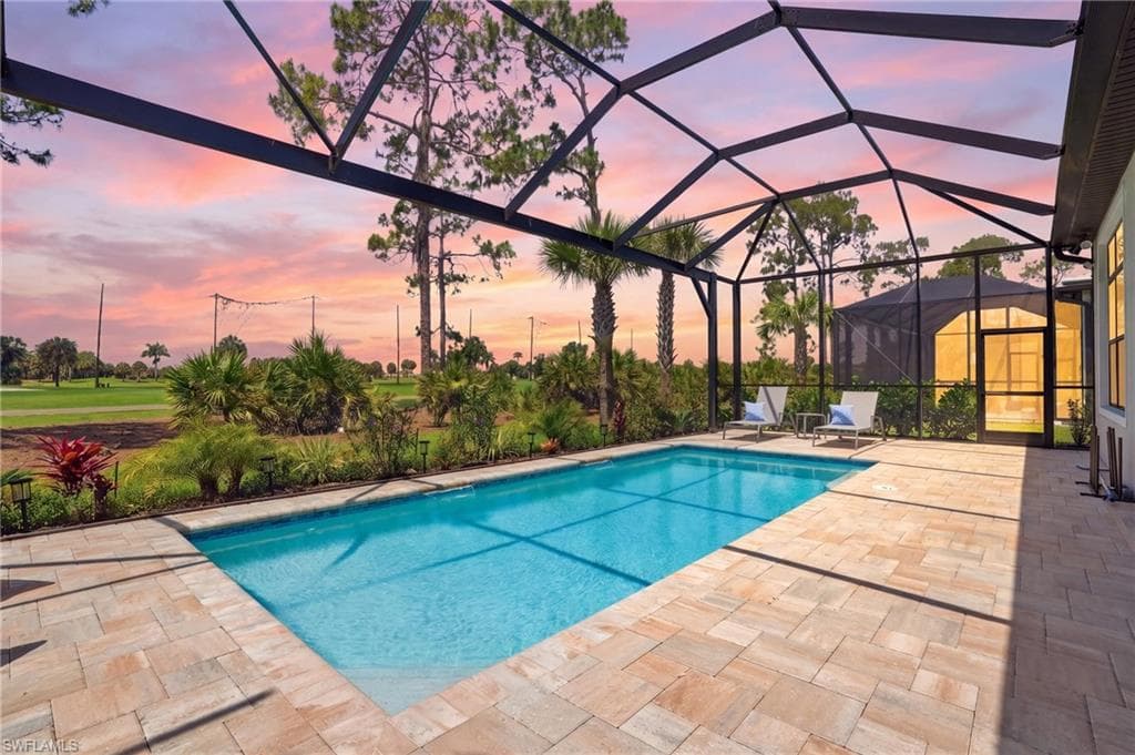 Enclosed swimming pool with paver decking, screened lanai, and surrounding landscaping