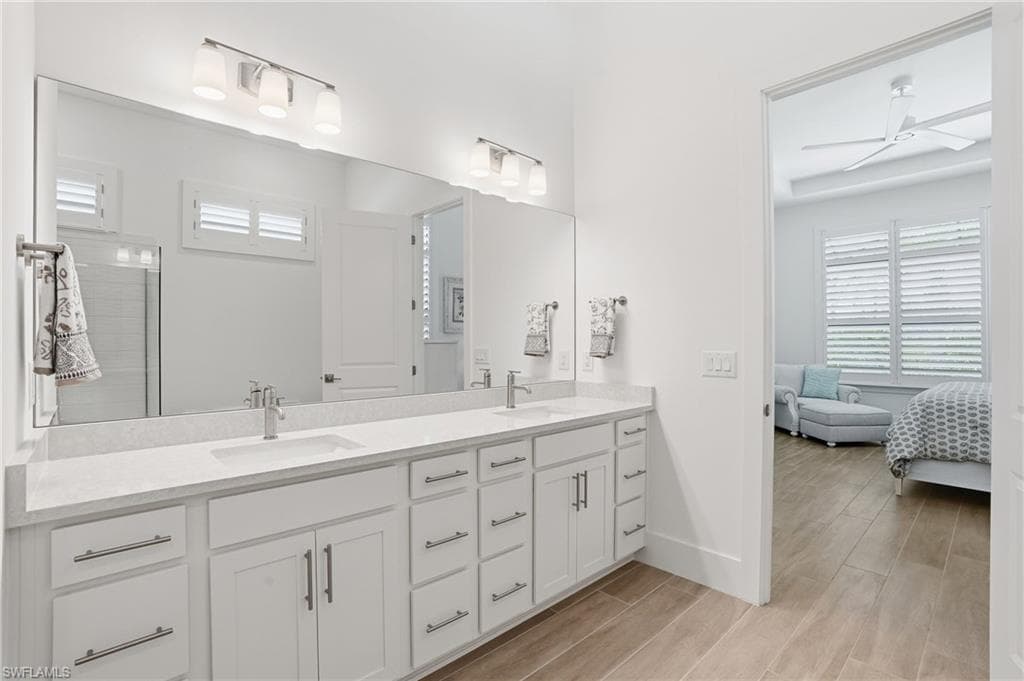 Dual vanity with white cabinetry, stone-finish countertops, and chrome fixtures