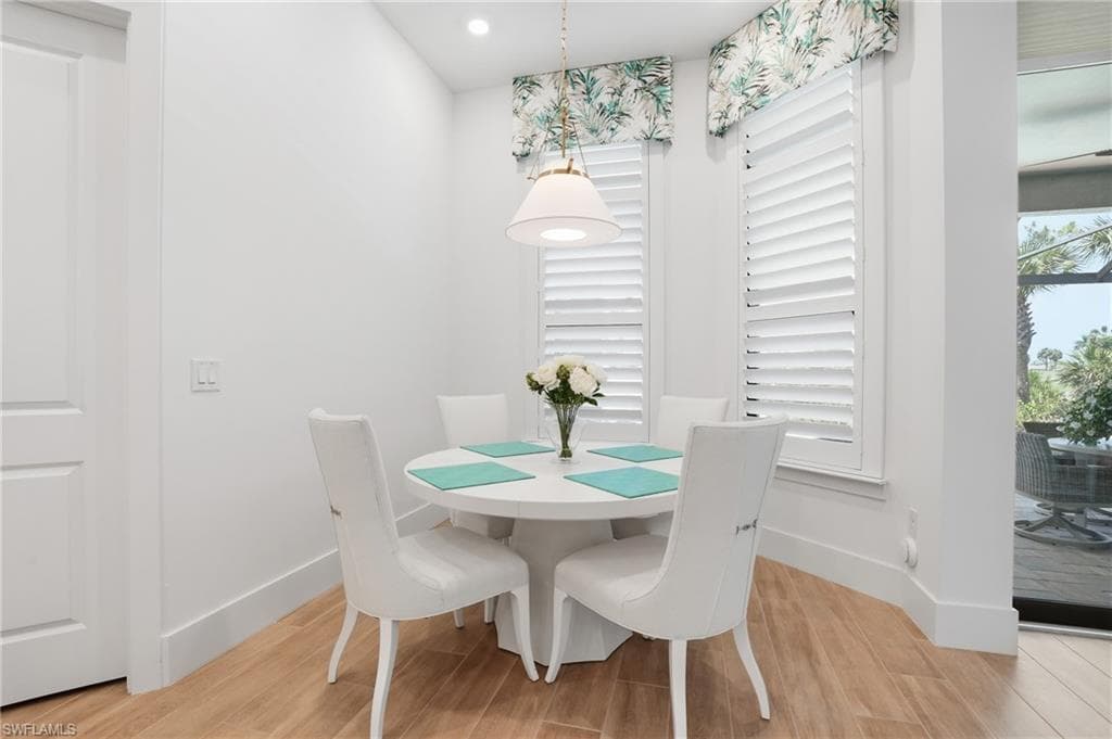 Bright dining nook featuring wood-finish flooring, white plantation shutters, and a pendant light fixture