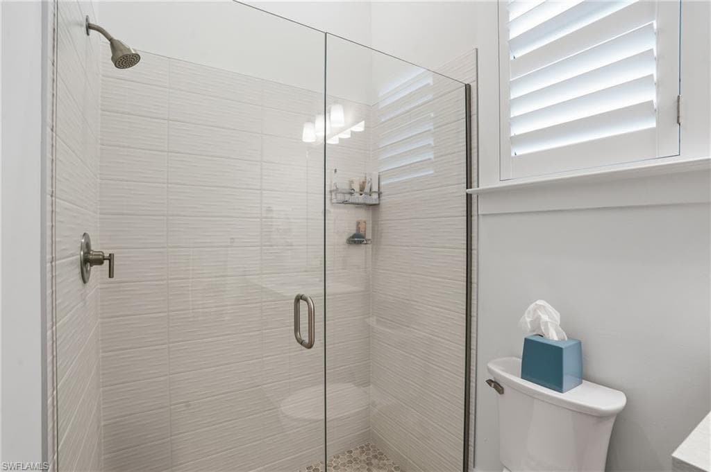 Glass-enclosed shower featuring a mosaic tile floor, horizontal textured wall tile, and brushed nickel fixtures