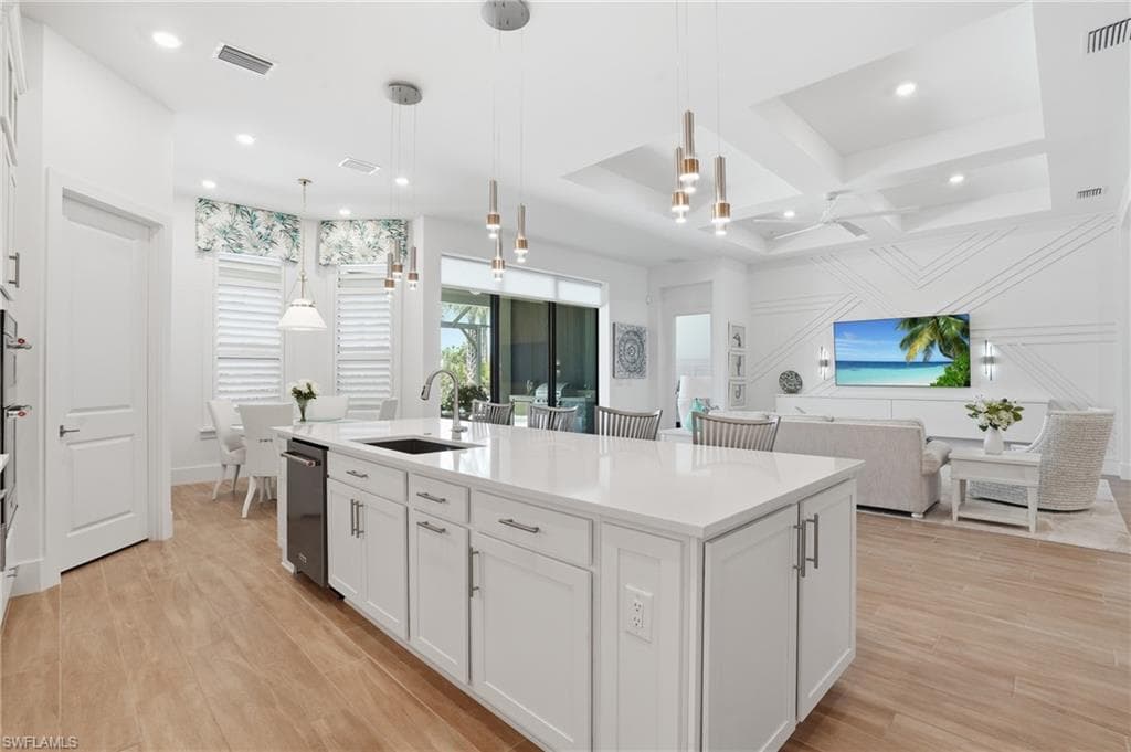 Open-concept living space featuring a substantial kitchen island with a white countertop, recessed lighting, and wood-finish flooring