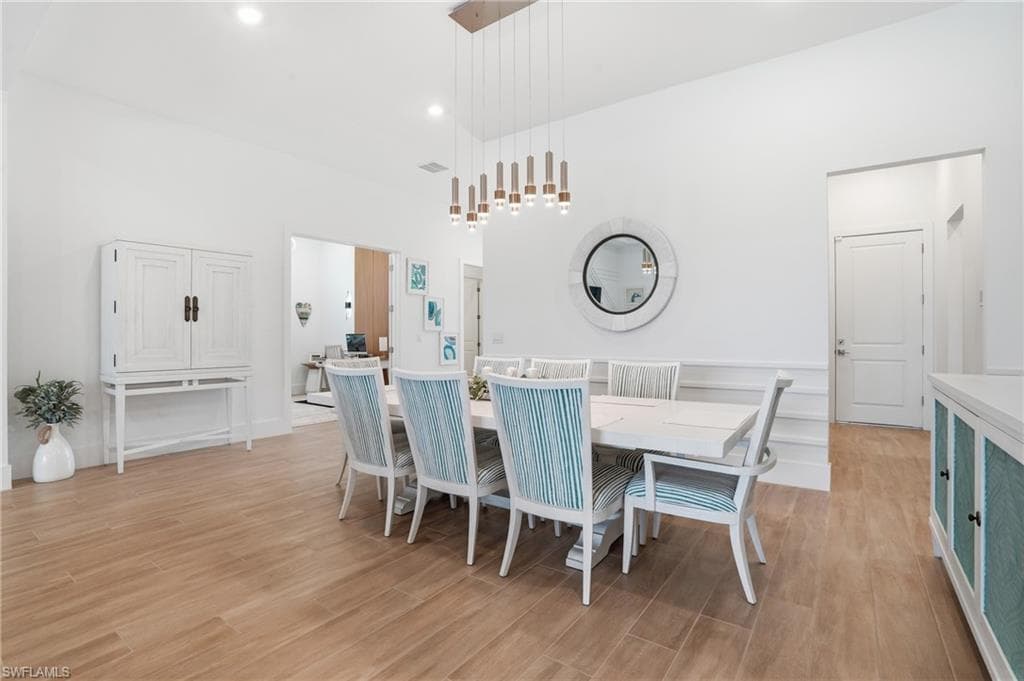Dining area featuring wood-finish flooring, white walls, and a modern linear chandelier