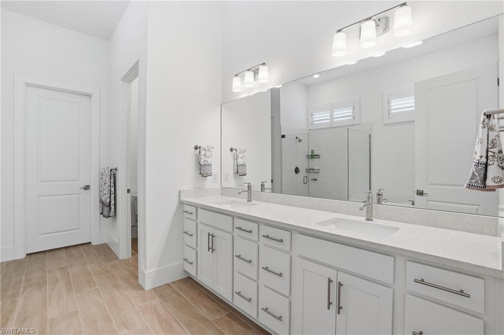 Spacious bathroom featuring a dual vanity with light-toned countertops, contemporary brushed nickel faucets, and extensive storage cabinetry