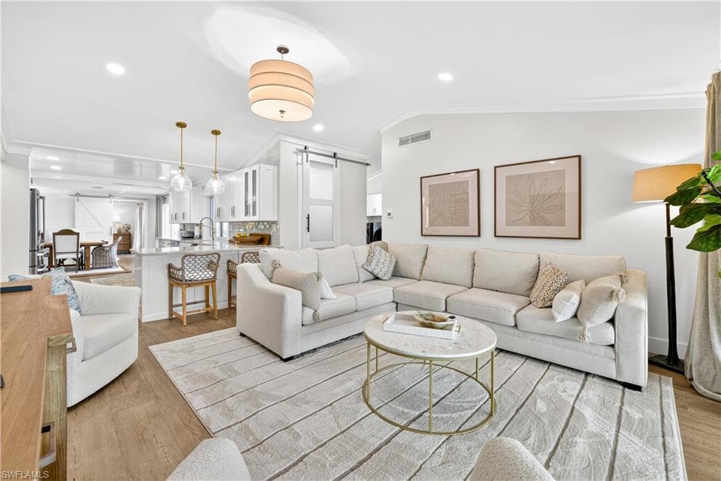 Open-concept living space featuring wood-finish flooring, recessed lighting, and crown molding