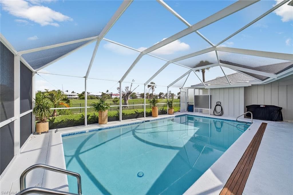 Screened swimming pool enclosure with a light blue pool, white decking, and integrated wood-finish accent strips