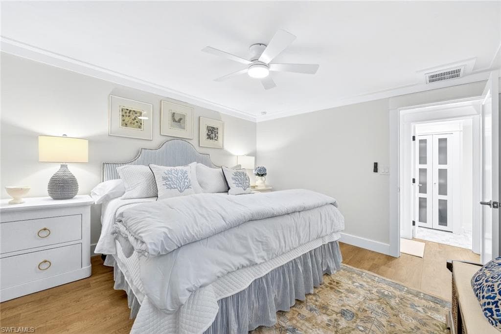 Spacious bedroom with wood-finish flooring and crown molding