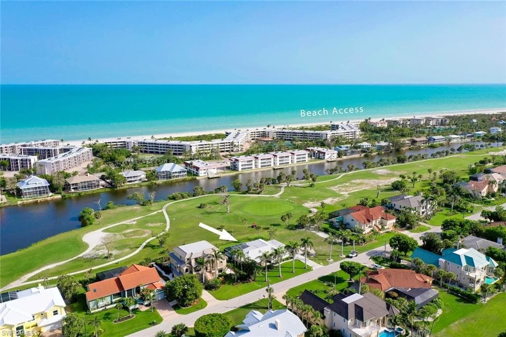 Aerial perspective showcasing a single-family residence situated on a golf course, with waterways and the Gulf of Mexico coastline in the background