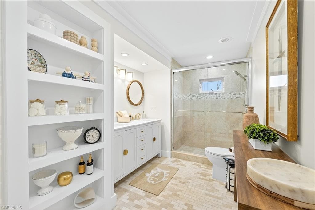 Contemporary bathroom featuring built-in shelving, a dual-sink vanity with gold-tone hardware, a tiled shower enclosure with sliding glass doors, a window within the shower, and mosaic tile flooring